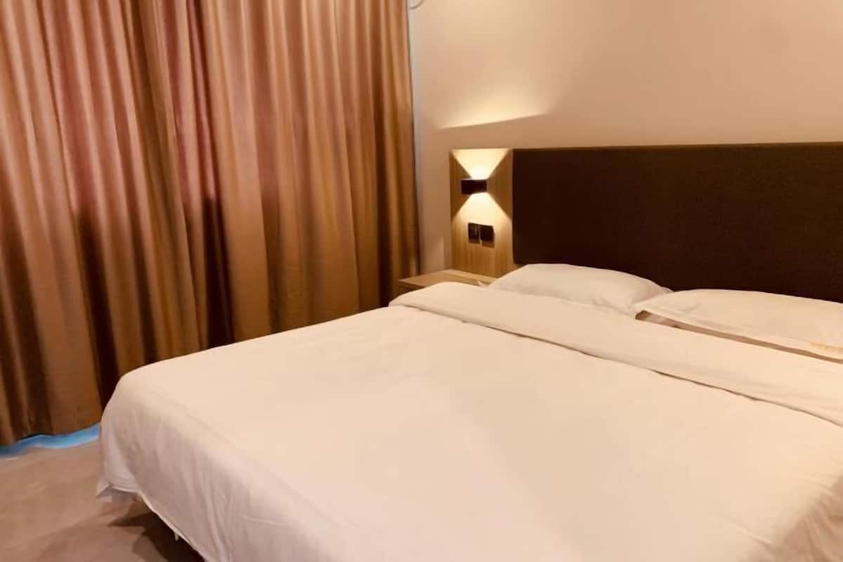 A hotel room with a large bed, two bedside tables, and a headboard with wall-mounted lighting.