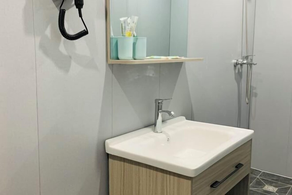 Een badkamer met een wit wastafel, een spiegel, een handdoekhouder en een douchehoek.