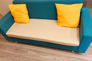 Ein türkisfarbenes Sofa mit zwei gelben Kissen und einer beigen Matratze.