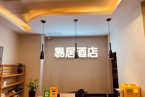 Un hall d'accueil d'hôtel avec une enseigne indiquant « Easy Stay Hotel » et un comptoir de réception.