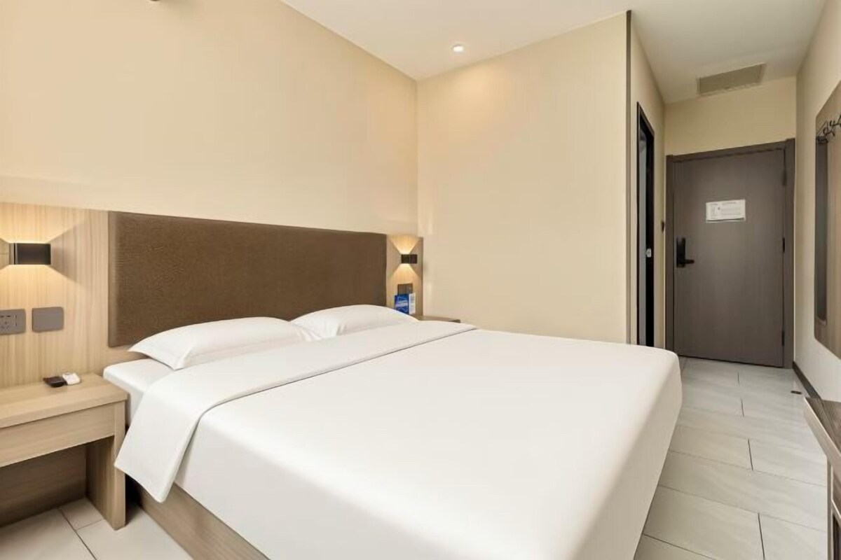 Una habitación de hotel con una cama grande, mesitas de noche y lámparas de pared.