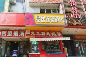A storefront with a prominent sign for 'Easy Living Hotel' and another sign for 'Xiang Huo Beer'.