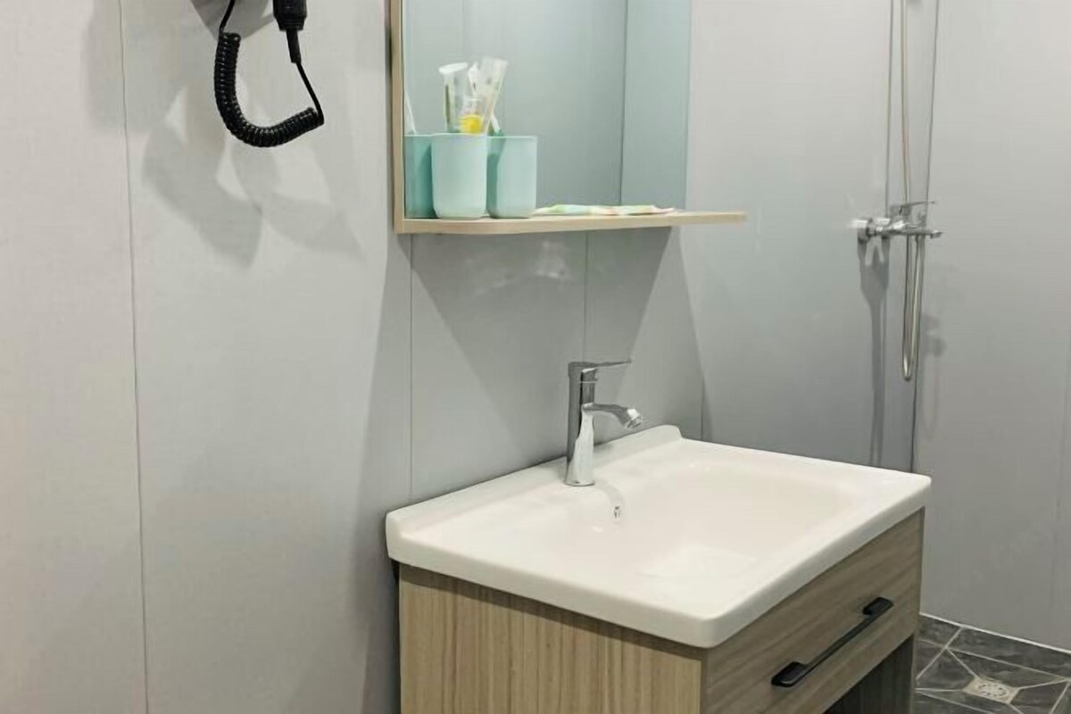 Een badkamer met een wit wastafel, een spiegel erboven en een handdoekrek.