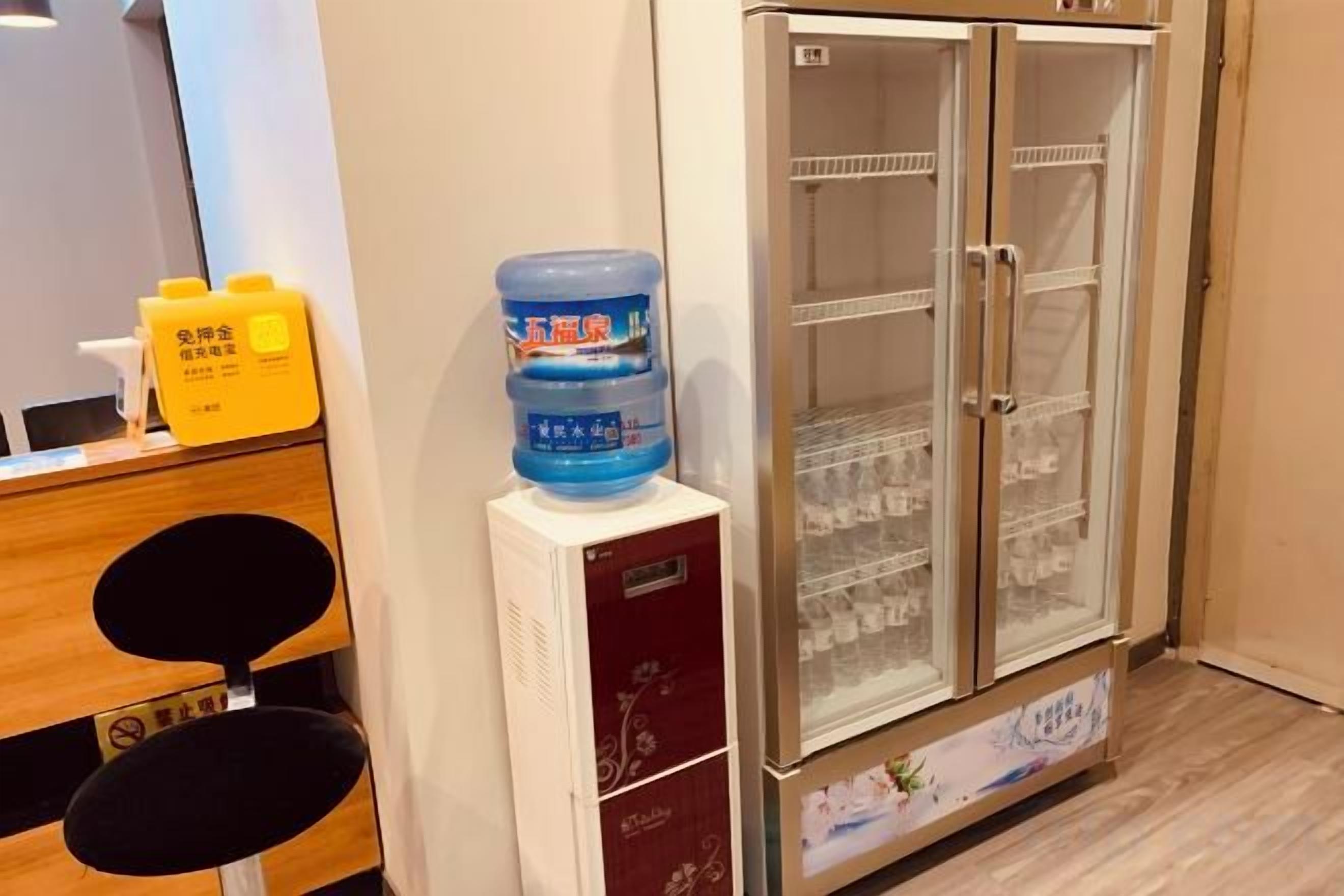A hotel room with a minibar, a water dispenser, and a refrigerator.