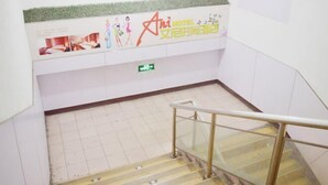 L’intérieur d’un hôtel avec un escalier, un sol carrelé et un mur orné d’une affiche.