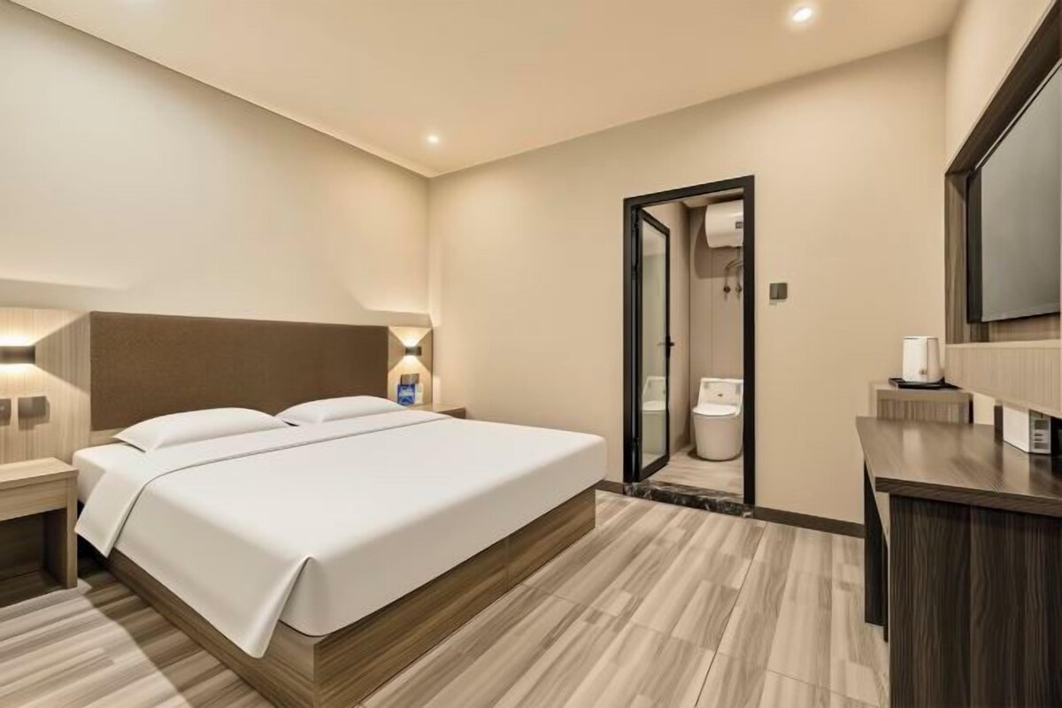 Una habitación de hotel con cama, mesita de noche, lámpara y espejo.