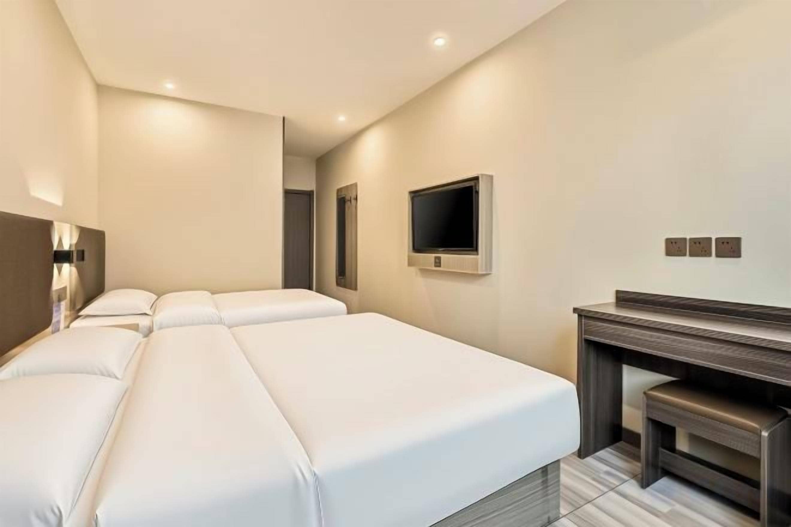 Una habitación de hotel con una cama grande, televisión y escritorio.