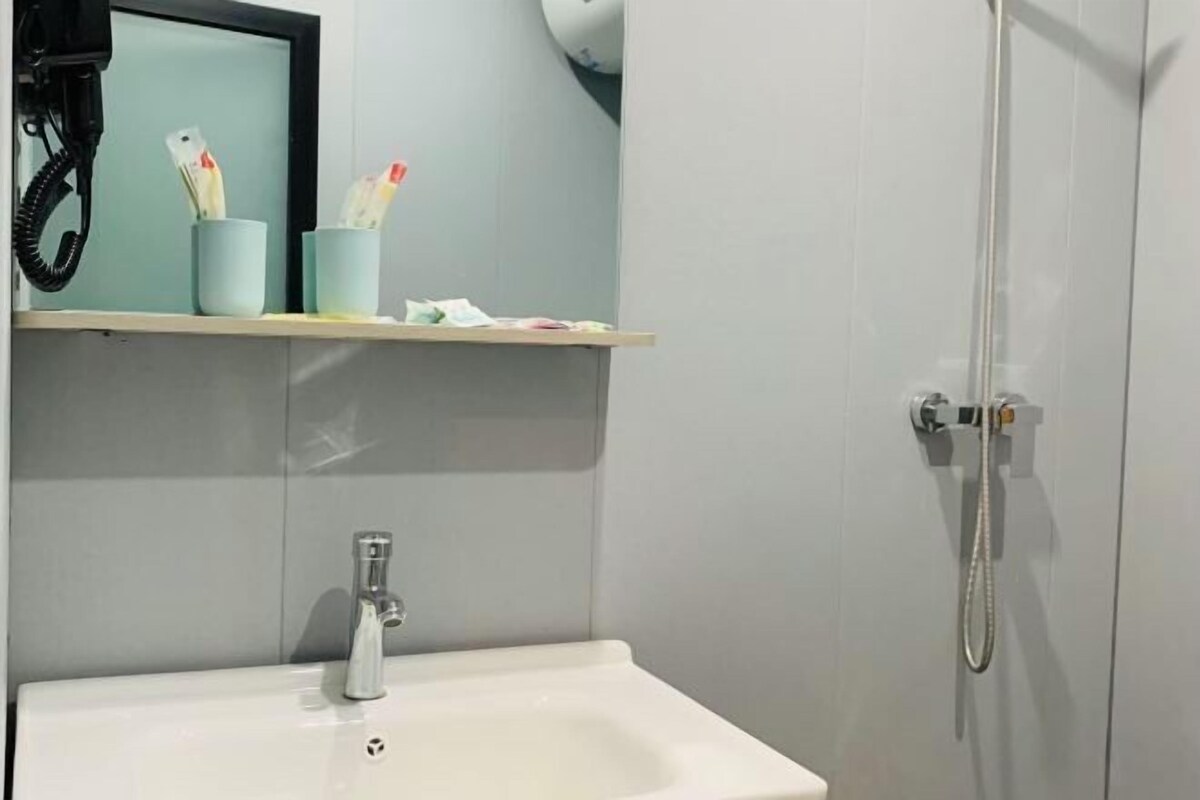 Een badkamer met een wastafel, spiegel en douche.