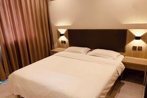 Une chambre d’hôtel avec un lit, deux tables de chevet et des lampes fixées au mur.