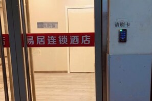 Een hotelingang met een bord waarop het type kamer staat aangegeven en een keypad voor toegang.