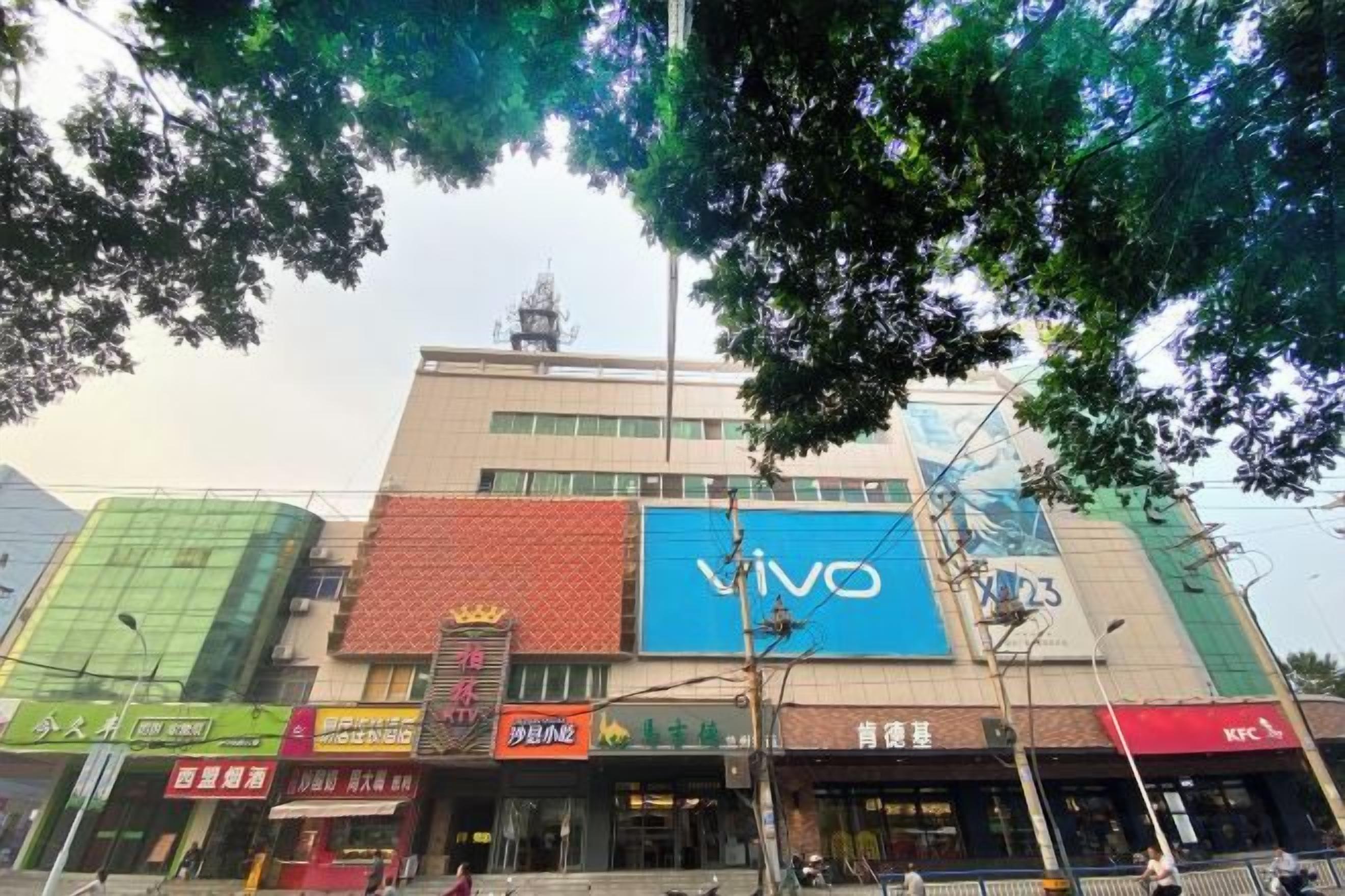 Un edificio de varios pisos con varios establecimientos comerciales en la planta baja, incluyendo una tienda Vivo.
