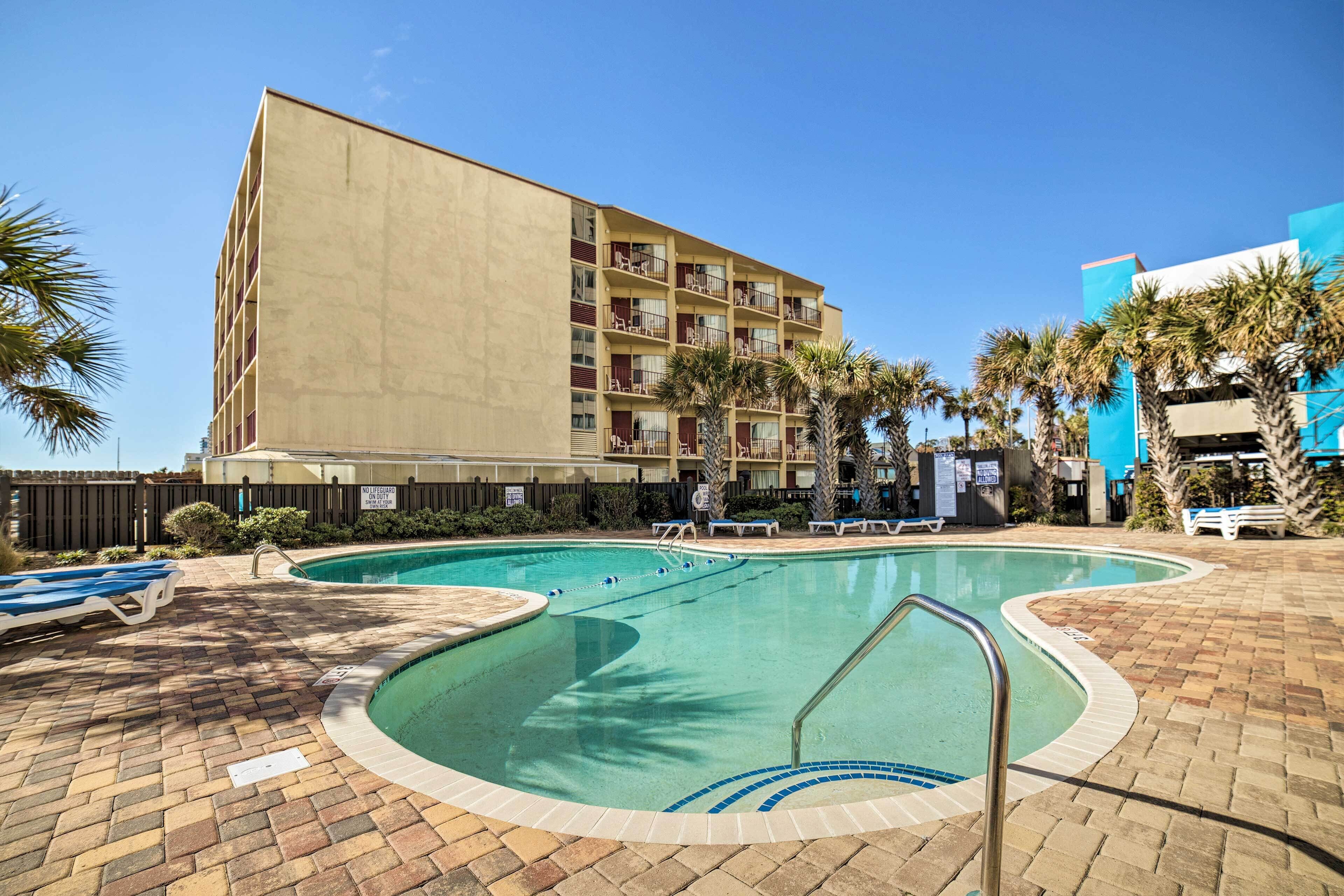 Un hotel con piscina, lettini e palme.