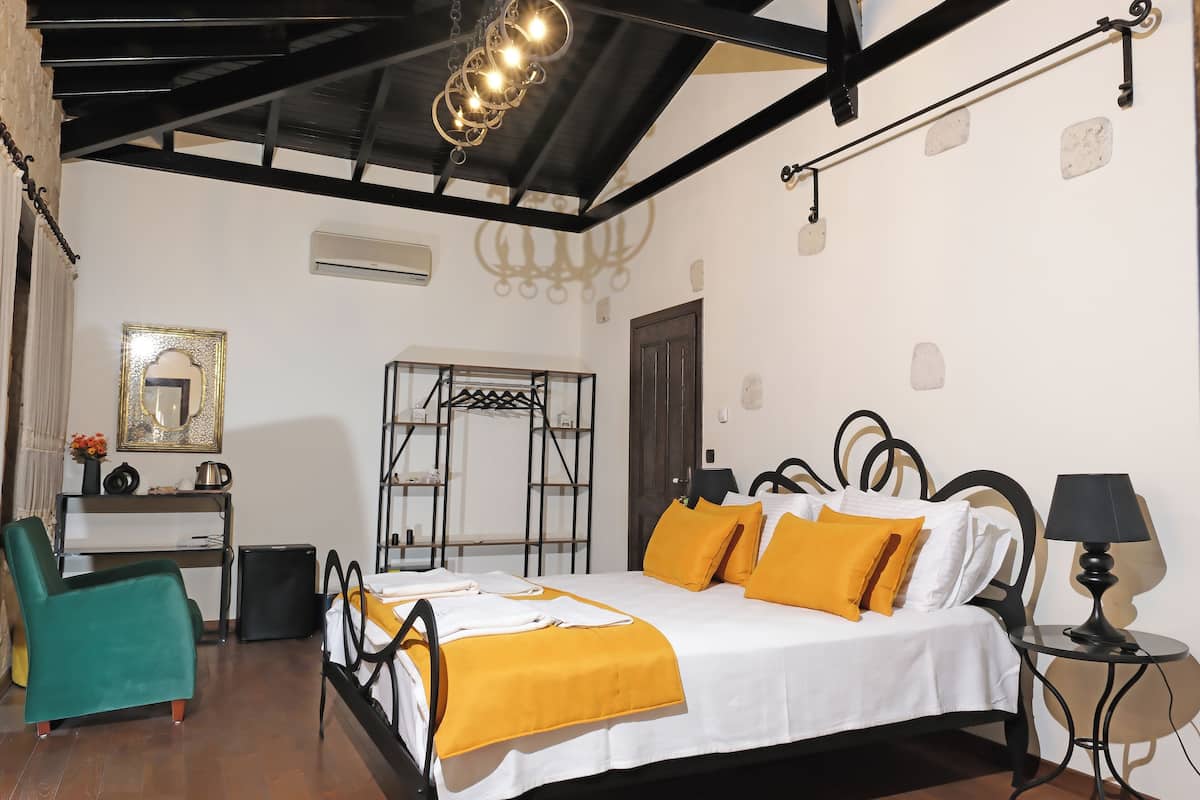 A hotel room with a bed, a desk, a chair, a wardrobe, and a chandelier.