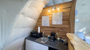 Een kleine keuken met een spoelbak, magnetron, koffiezetapparaat en houten details.