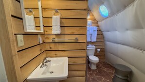 Een kleine badkamer met houten lambrisering, een witte wasbak, een toilet en een handdoekhouder.