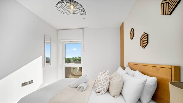 Une chambre à coucher moderne avec un grand lit, une vue par la fenêtre et un luminaire au plafond original.