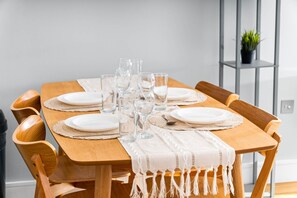 Una mesa de madera dispuesta con platos, vasos y un mantel individual.