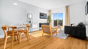 Un salon moderne comprenant un coin repas, un canapé noir, des meubles en bois et une grande fenêtre offrant une belle vue.