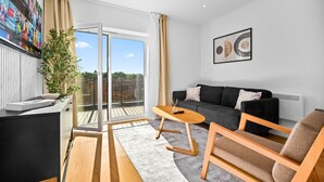 Un salon moderne avec un canapé, des fauteuils, une table basse et un téléviseur fixé au mur.