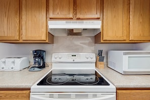 Efficient kitchen with stovetop, oven, coffee maker, toaster, and microwave.