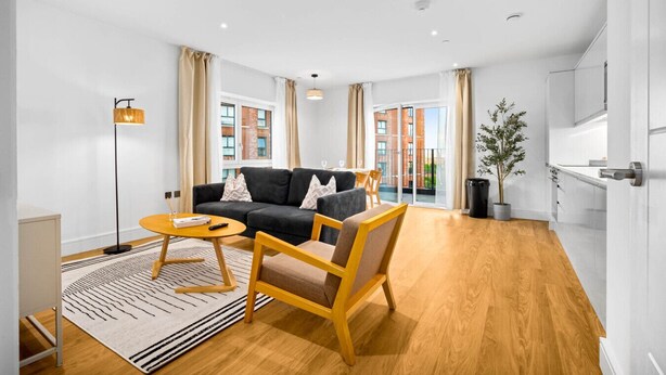 Una sala de estar moderna con un sofá, un sillón y una mesa de centro, una mesita auxiliar y una planta en maceta.