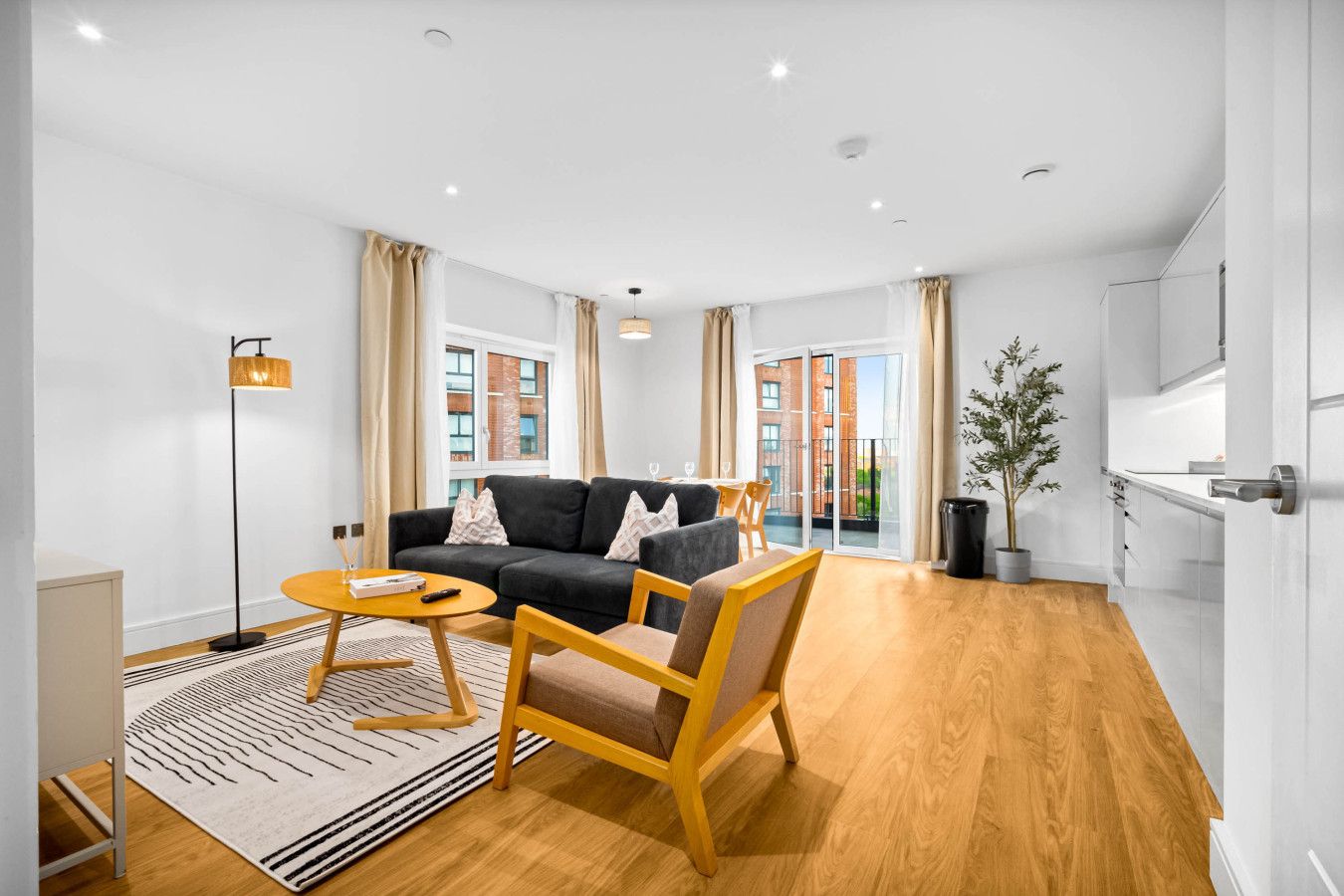 Un salon moderne comprenant un canapé, un fauteuil et une table basse, ainsi qu’une petite table d’appoint et une plante en pot.