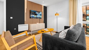 Una sala de estar moderna con una pared de acento negra, un televisor montado, un sofá, una mesa de centro y una lámpara de pie.