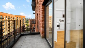 Un apartamento moderno con balcón, ventanas amplias y zona de cocina.