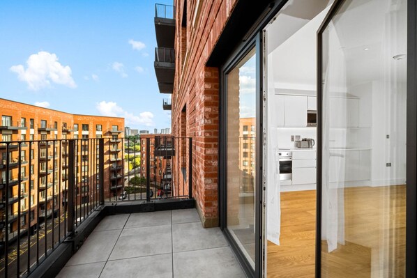 Un appartement moderne doté d’un balcon, de grandes fenêtres et d’un coin cuisine.