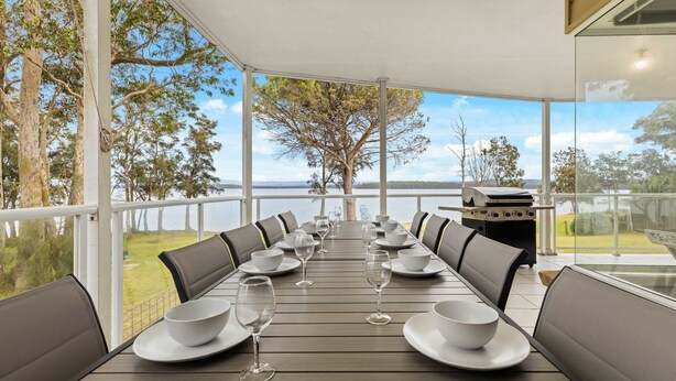 Un espace extérieur abrité où l’on peut prendre ses repas, avec vue sur un lac et des arbres.