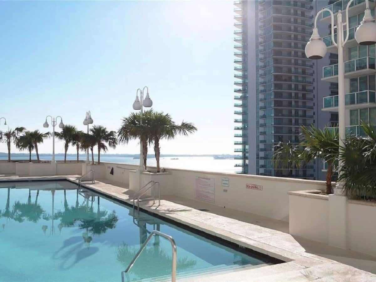 Una piscina con vista al océano y un edificio alto al fondo.