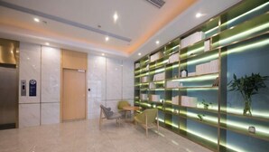 A modern lobby with a marble floor, a reception desk, and a wall of illuminated shelves. - Starway Hotel Shanghai Wujiaochang Changhai H (Shanghai)