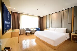A hotel room with a large bed, a desk, two chairs, a small table, and a TV on the wall. - Starway Hotel Shanghai Wujiaochang Changhai H (Shanghai)