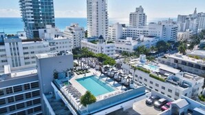 A rooftop pool with lounge chairs and umbrellas, surrounded by high-rise buildings and palm trees. - Luxury Miami Beach Apartment with Rooftop Pool (Miami Beach)