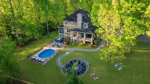 A large house with a swimming pool, outdoor seating, and a fire pit. - 6 King Bedrms! Heated Pool. 2 Hot Tubs. Game Room. 3 Fire Pits. Sleeps 22! (Fletcher)