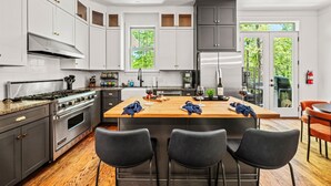 A modern kitchen with a central island, stainless steel appliances, and a view to the outdoors. - 6 King Bedrms! Heated Pool. 2 Hot Tubs. Game Room. 3 Fire Pits. Sleeps 22! (Fletcher)