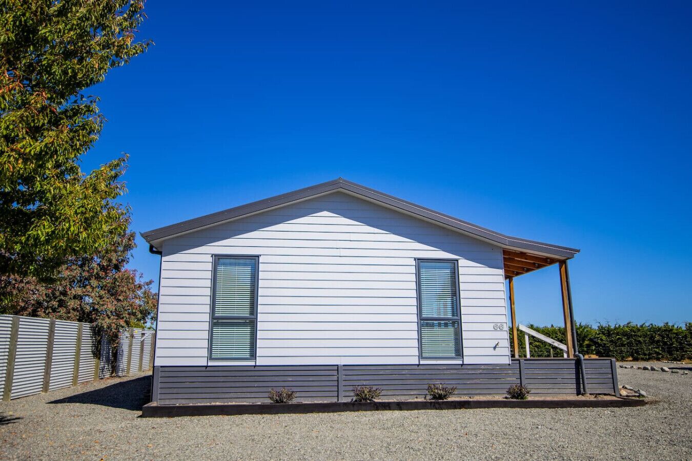 Une maison de plain-pied avec un toit à pignon, une véranda et une allée gravillonnée.
