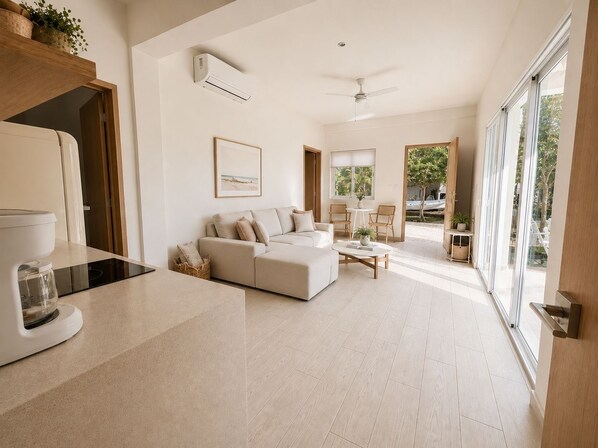 A modern living room with a sofa, coffee table, and a view of the outdoors. - Oceanfront Bliss l 3 BR Retreat + Private Pickleball Court (Isla Mujeres)