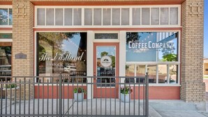 The Eastland Historic Hotel with a coffee company sign, a brick facade, and a metal fence in front. - The Arlington Apartment (Eastland)
