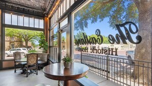 A hotel interior with a large window, a round table, and two chairs. - The Arlington Apartment (Eastland)