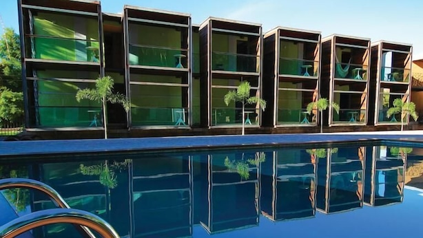 A modern building with multiple balconies, a swimming pool, and potted plants. - Pousada Estação Bananeiras (Bananeiras)