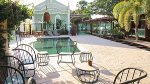 A poolside area with outdoor seating, a pool, and a building with a dome in the background. - Pousada Estação Bananeiras (Bananeiras)