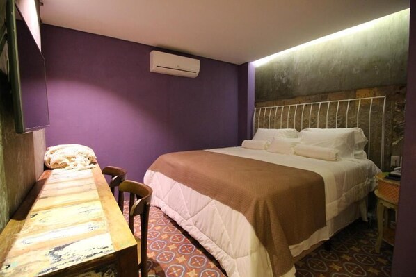 Quarto com cama, mesa de madeira e uma cadeira.