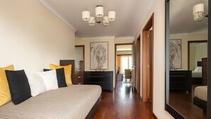 A bedroom with a large bed, a dresser, a mirror, and a hallway leading to another room. - Perla do Oceano – Funchal Sea View with XL Terrace (Funchal)
