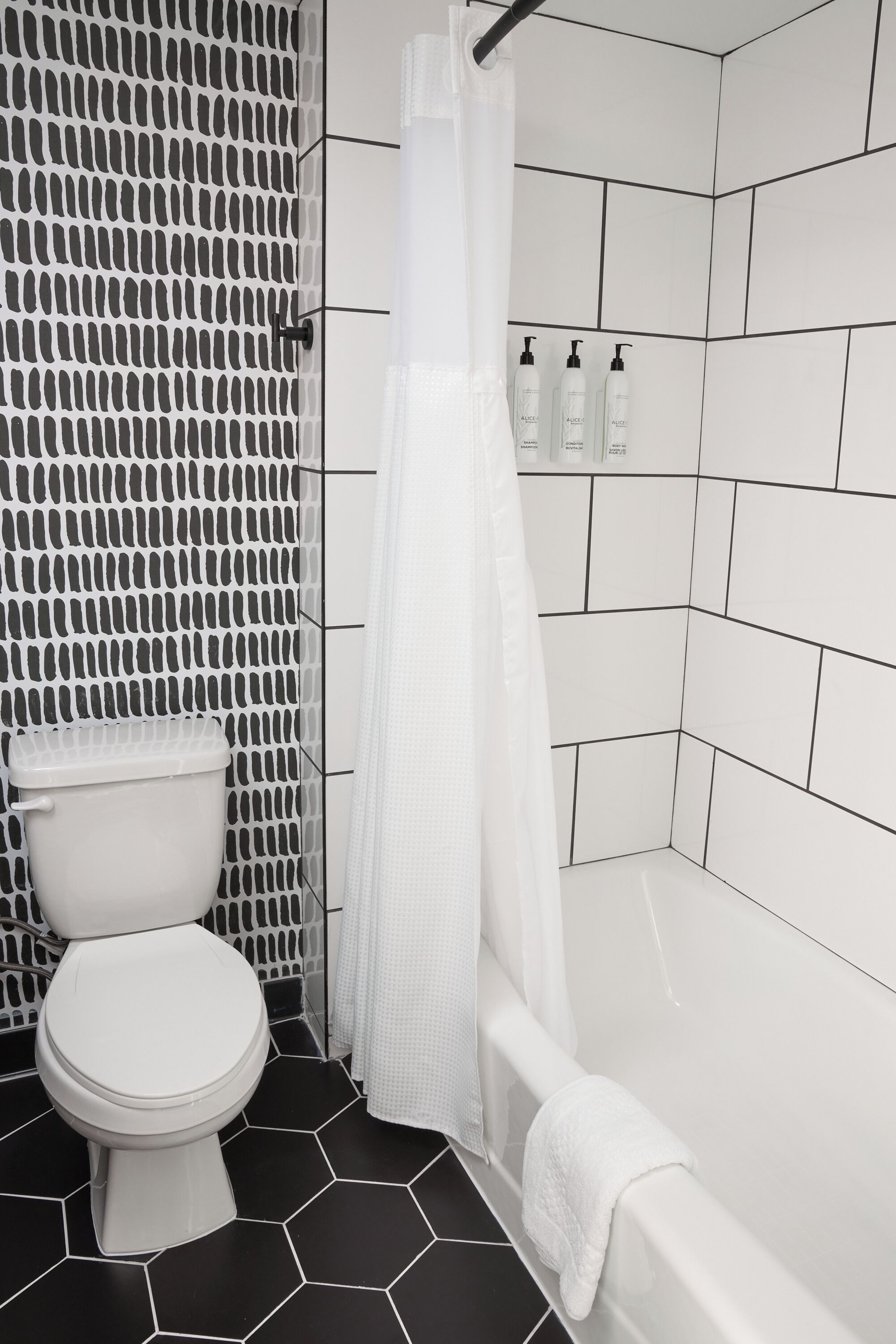 Een badkamer met toilet, douche met een witte gordijn en een bad.