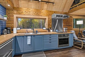 Una cocina moderna con paneles de madera, un ventanal grande y electrodomésticos integrados.