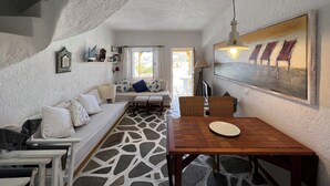 A cozy room with a stone-patterned floor, a wooden dining table, and a sofa with cushions.
