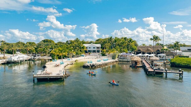 Un port de plaisance avec des bateaux, un quai et un bâtiment doté d’un toit de chaume.