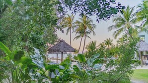 Un complexe hôtelier tropical doté de bungalows aux toits de chaume, de palmiers et d’une végétation luxuriante.