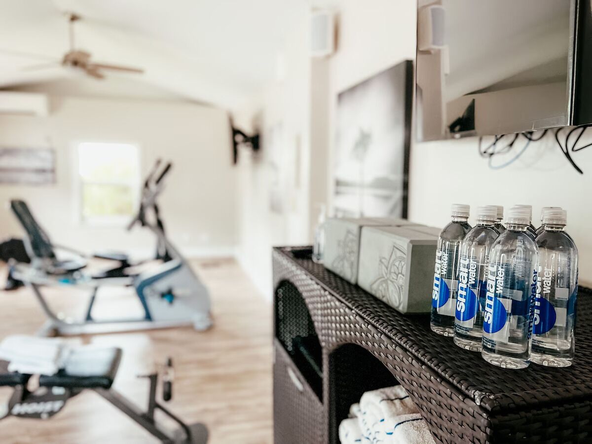 A home gym with exercise equipment, a television, and water bottles on a shelf.
